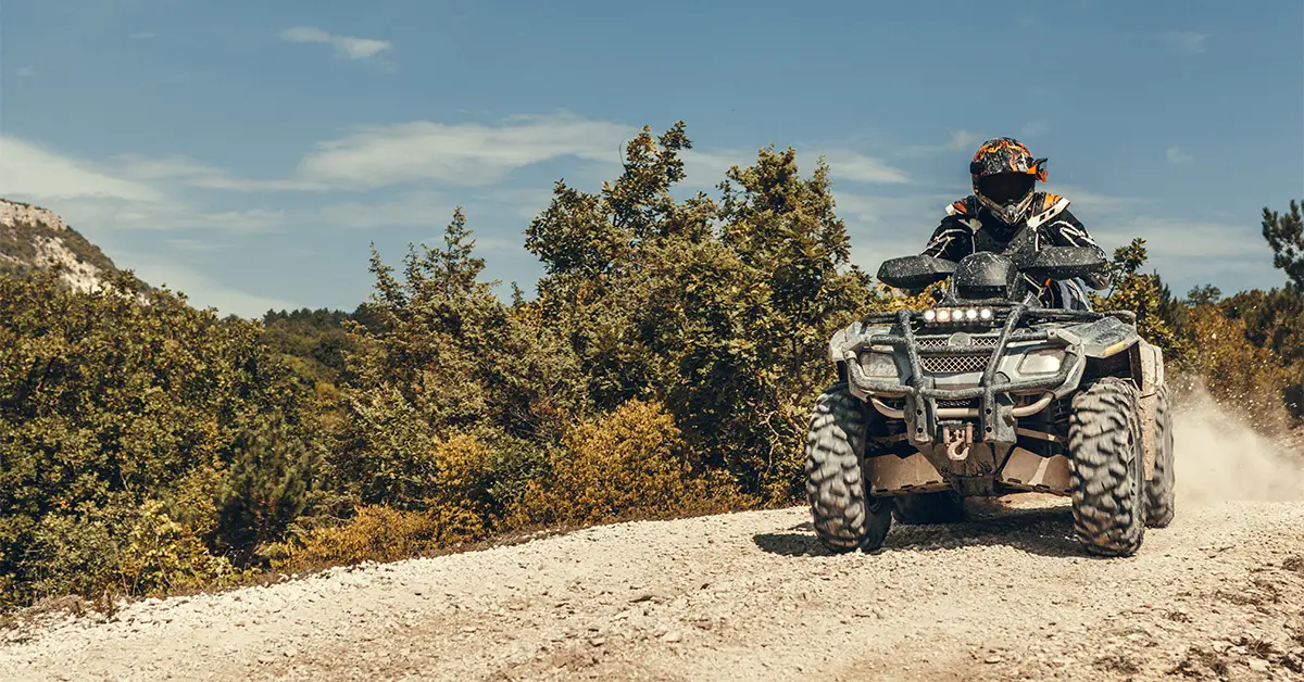 Modern ATV with fuel injection engine, riding on a road.