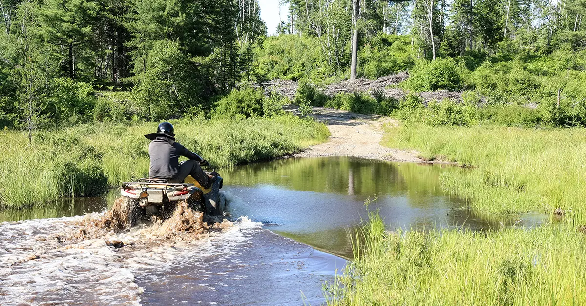 ATV driver in deep water with their feets up