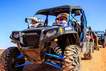 UTVs lined up in the desert, with a Polaris RZR in the front